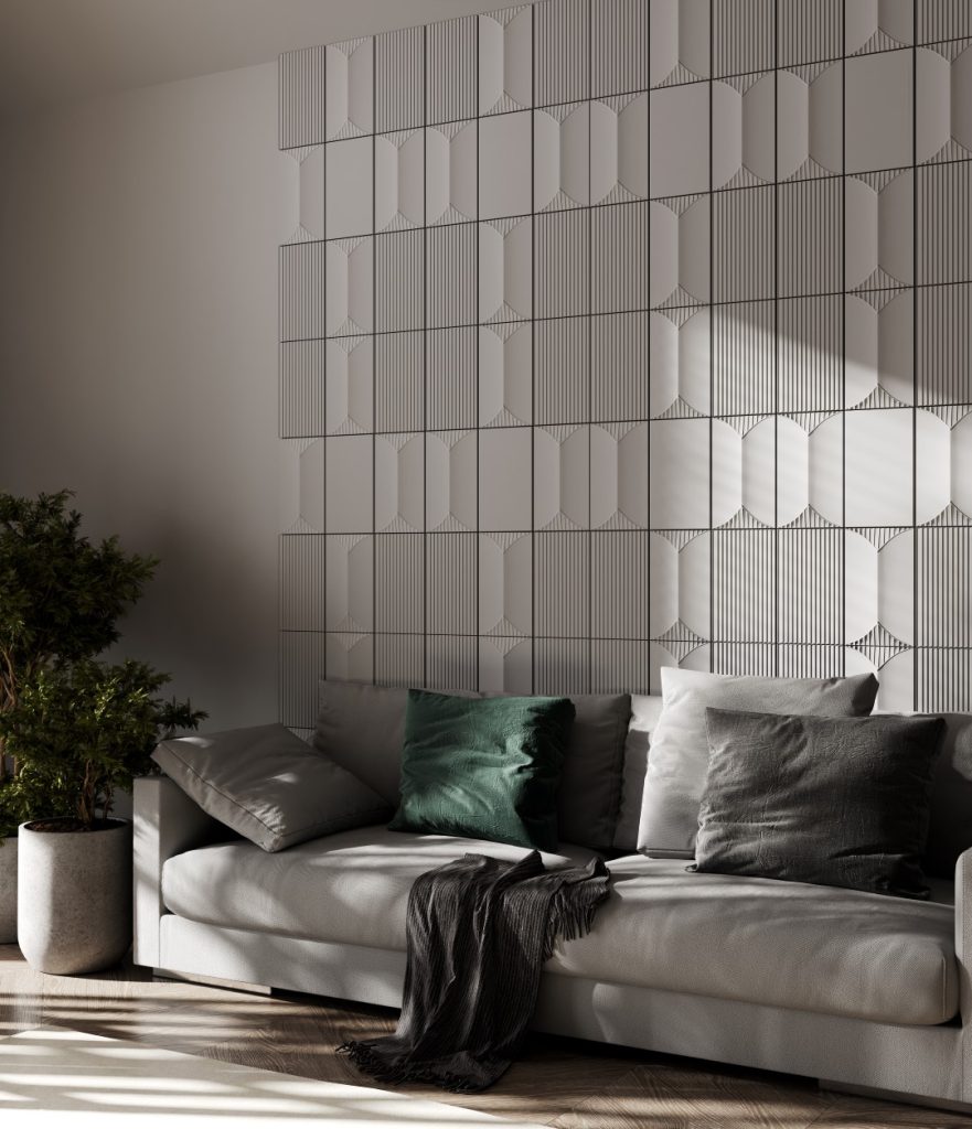 Sunlight falls across a serene modern living room, highlighting a gray sofa with dark green and gray cushions, a potted tree, and a geometric wall.