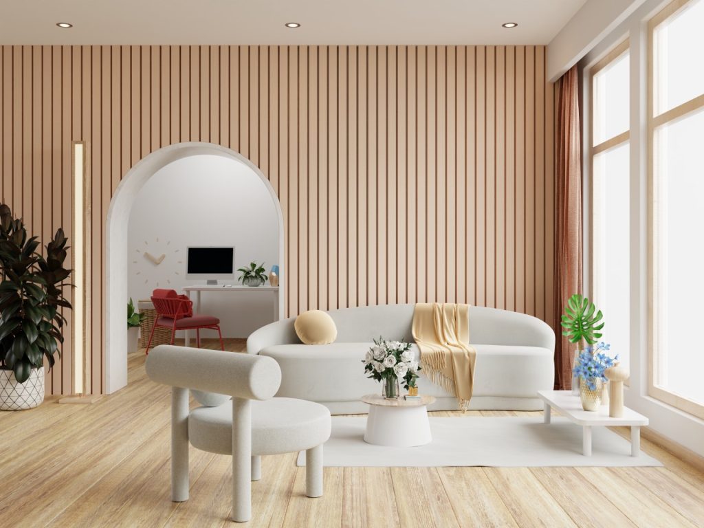 Sunlit modern living room with a curved white sofa, sculptural chair, flowers, and plants against a striped wood wall; warm, calm, minimalist decor.