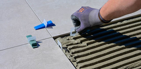 A person operates a tile cutter, carefully cutting a tile for a home improvement project.